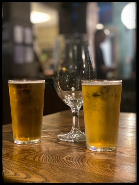 Image of an empty pint glass next to a half pint of cider and a half pint of lager