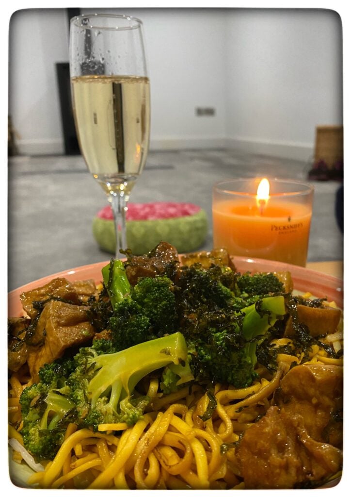 Image of a plaet of Chinese takeway and a glass of sparkling wine