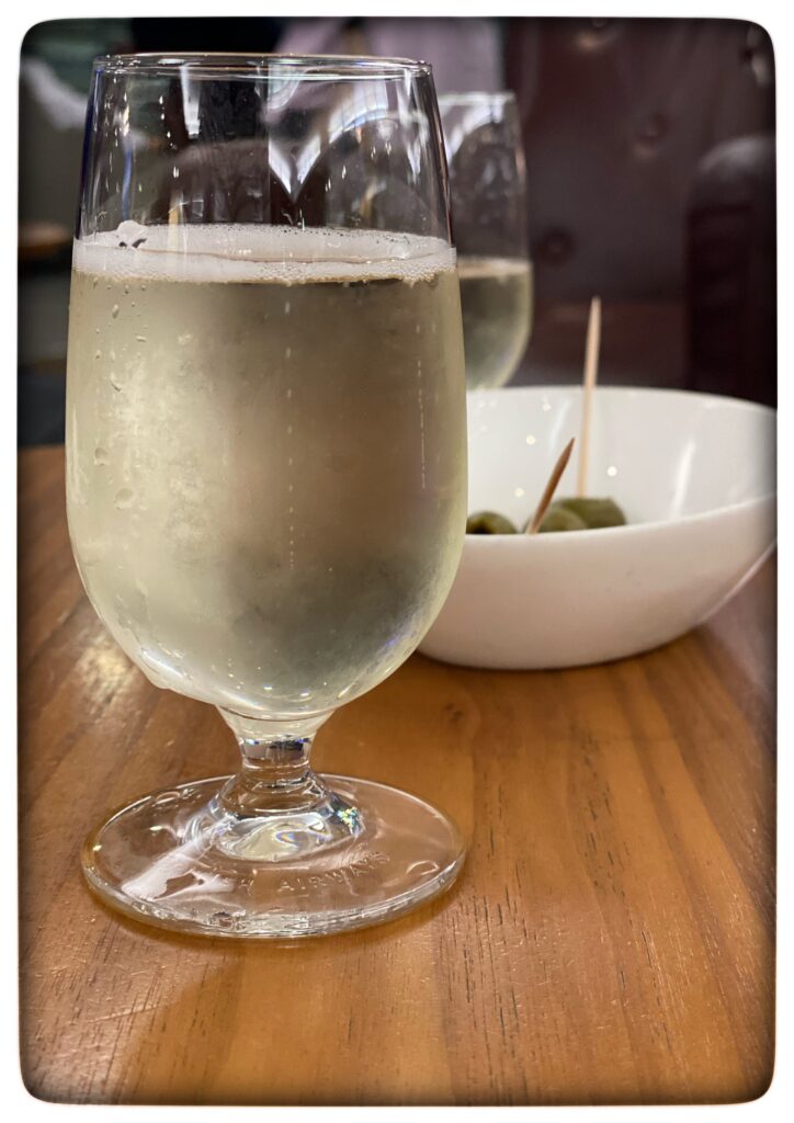 Image of a small glass of sparkling wine and a bowl of olives