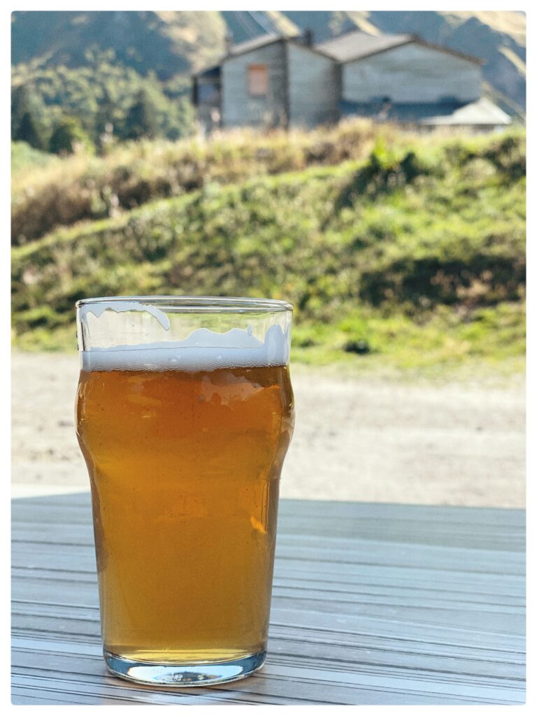 Image of a glass of beer in front of a mountain hut